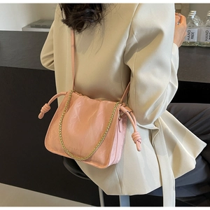 Detail of light pink pleated bucket bag with gold chain and knot drawstring accents
