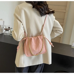 Detailed view of pink pleated bucket bag with gold chain and drawstring knots