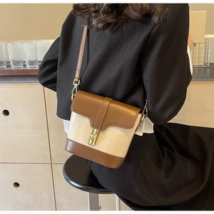 Detail view of contrast bucket bag with gold clasp and elegant textured finish