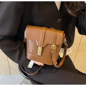 Detail of caramel brown crossbody bag with gold twist lock and adjustable strap