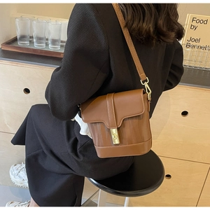 Detail of vintage brown leather bucket bag featuring vertical stripes and a gold twist lock