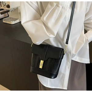 Detail of vintage black bucket bag with golden twist lock and wavy leather texture