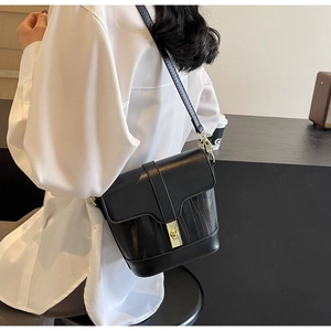 Close-up of black crossbody bucket bag with vertical texture and gold metal clasp
