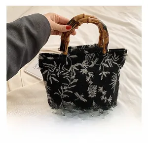 Détail du sac cabas vintage en toile à motifs floraux et anses en bambou naturel