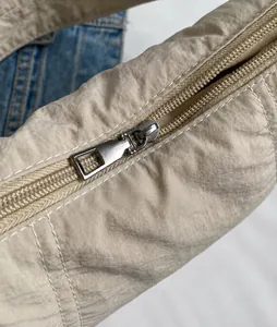 Κοντινό πλάνο ασημί μεταλλικού φερμουάρ σε μπεζ νάιλον τσάντα με εξαιρετική ραφή