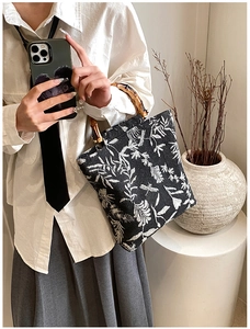 Détail du sac en toile rétro avec poignées en bambou et broderies florales élégantes