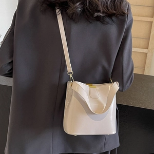 Sac seau crème élégant en cuir verni brillant avec des accessoires dorés sur l'épaule