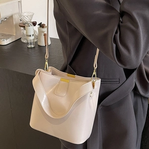 Sac seau élégant en cuir verni crème avec détails dorés et bandoulière pour femme