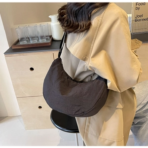 Détail du sac demi-lune en nylon noir avec plis texturés et fermeture éclair durable