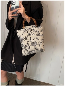 Détail de l'anse en bambou sur un sac en toile crème avec motifs végétaux de libellules