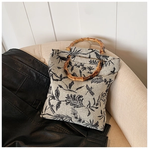 Détail du sac cabas en toile fleurie avec des poignées en bambou naturel sur un canapé