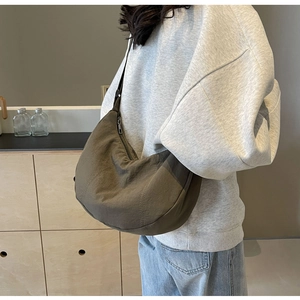Sac demi-lune en nylon vert olive porté à l'épaule par un mannequin pour le quotidien
