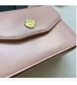 Macro detail of pink leather crossbody bag showing gold floral letter C metal hardware
