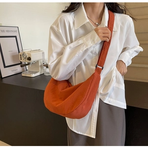 Vue latérale du sac bandoulière en nylon caramel sur mannequin dans un café moderne