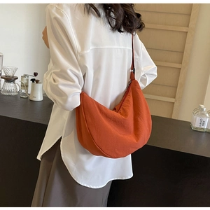 Détail d'un sac bandoulière orange en nylon en forme de croissant avec sangle réglable