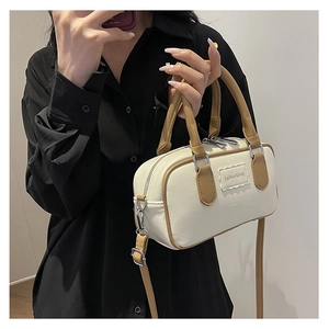 Close-up of cream-colored Boston bag with brown trim and Fashion & bag logo detail