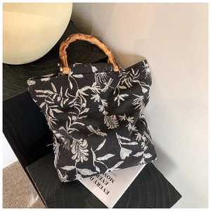Détail d'un sac cabas en toile noire à motif floral et poignées en bambou naturel