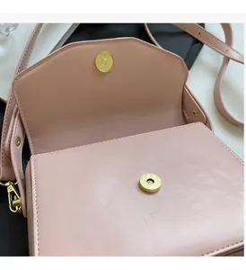 Detail of pink crossbody bag showing the pale gold magnetic buckle and synthetic leather