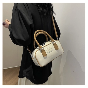 Rear view of a model wearing a chic two-tone crossbody bowling bag in white and brown