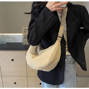 Sac bandoulière demi-lune en nylon beige avec sangle réglable dans un intérieur moderne