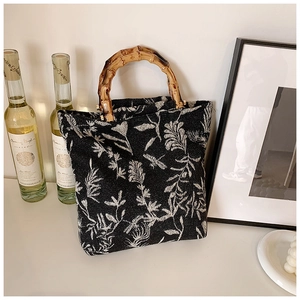 Vue détaillée du sac cabas en toile fleurie noire avec poignées en bambou naturel
