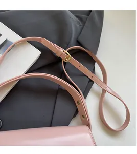 Detail of pink glossy leather shoulder bag showing adjustable strap with gold metal buckle