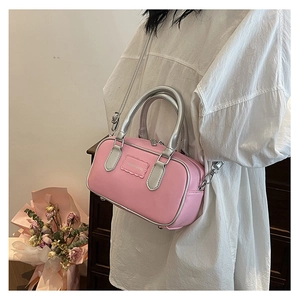 Side view of a pink and silver two-tone crossbody box bag worn by a model in a room
