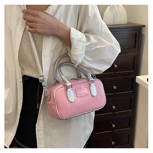 Pink mini cylindrical bag with silver handles shown in a side view on a model