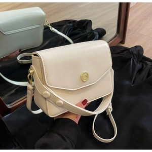 Close-up of cream flap crossbody bag with gold round buckle and mirror reflection detail