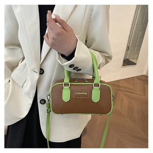 Close-up of a brown leather mini Boston bag with green trim and silver hardware details