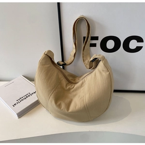 Détail de la large bandoulière réglable et de la boucle sur le sac demi-lune en nylon beige