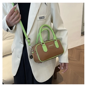 Detail of a brown and neon green contrast crossbody bag worn with a white blazer