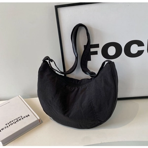 Détail du sac croissant en nylon noir avec une finition texturée et une bandoulière réglable