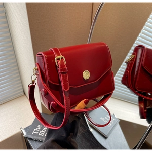 Close-up of deep red glossy leather bag featuring a decorative gold-tone circular lock