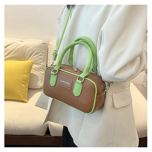 Detail view of brown and green contrast crossbody bag with leather texture and top handle