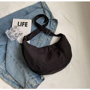 Gros plan détaillé d'un sac demi-lune en nylon noir sur une veste en jean décontractée