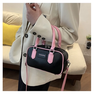 Close-up of stylish black and pink Boston bag styled with a beige blazer outfit