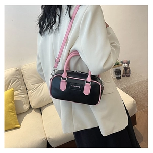 Detail of fashion crossbody box bag in black and pink leather on a beige sofa