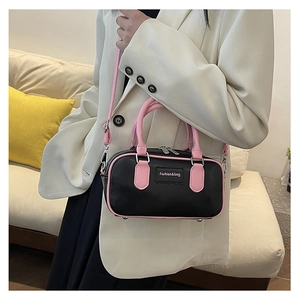 Detail of compact black and pink contrast crossbody bag with silver hardware on a model