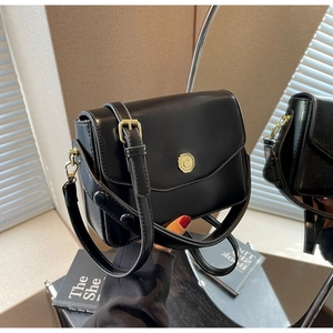 Detail of black glossy PU leather handbag featuring a vintage gold camellia flower lock