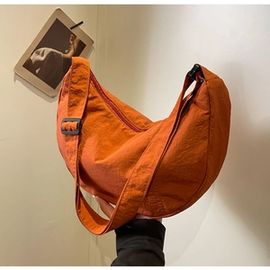 Détail du sac croissant en nylon orange brûlé montrant la texture plissée et la sangle