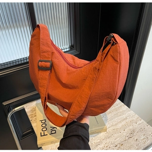 Détail du sac demi-lune en nylon orange brûlé avec large bandoulière réglable