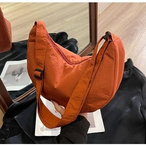 Détail du sac croissant en nylon orange vif avec bandoulière réglable et fermeture à glissière