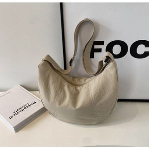Détail de la bandoulière réglable et de la texture en nylon du sac croissant beige