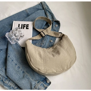 Détail du sac demi-lune en nylon kaki avec bandoulière réglable et tissu texturé