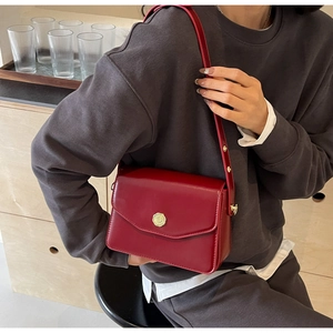 Detail of burgundy leather crossbody bag with golden metal buckle and adjustable strap