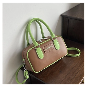 Detail of contrast brown leather handbag with neon green straps and silver zipper finish