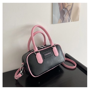 Detail of pink and black contrast bowling bag showing double zippers and leather texture