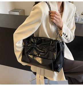 Détail du sac cabas noir brillant avec double nœud et bandoulière chaîne argentée