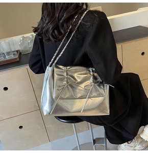 Détail du sac cabas argenté métallisé avec texture plissée et nœuds décoratifs en ruban